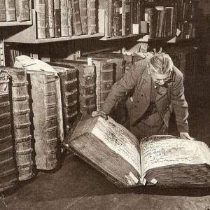 A woman examining giant books in the Prague Castle Archives. Czech Republic, 1940s.